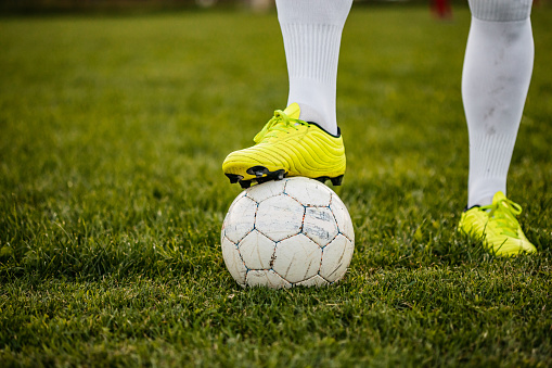 Feet of soccer football player standing with the ball, close up.