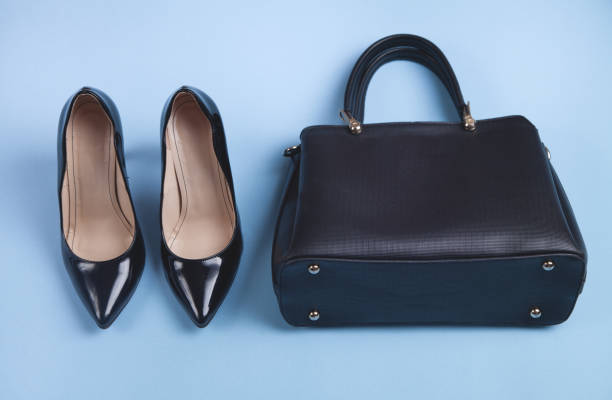 istock Black high heeled shoes and bag on blue background. 1310478274