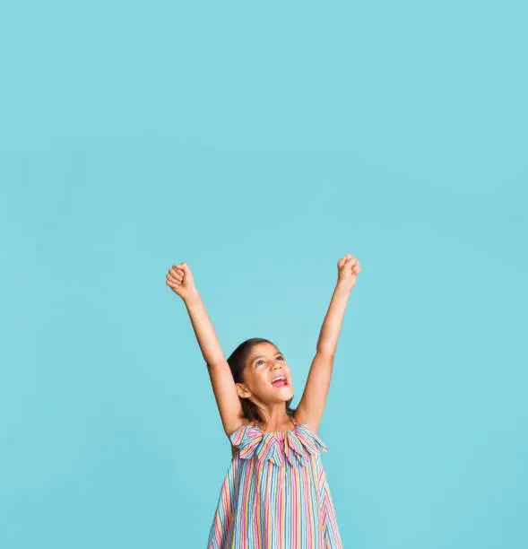 Photo of Pretty little girl raising both her arms up