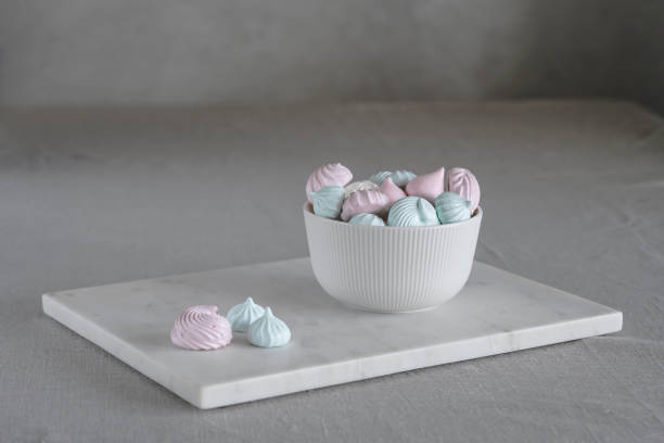 istock Multicolored meringue in a white plate on a light background stock photo 1310480446