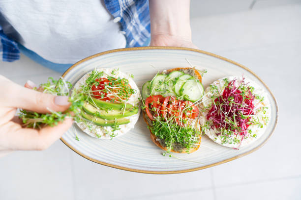 istock Female hands holding a plate with toasts made with fresh microgreen sprouts 1310480785