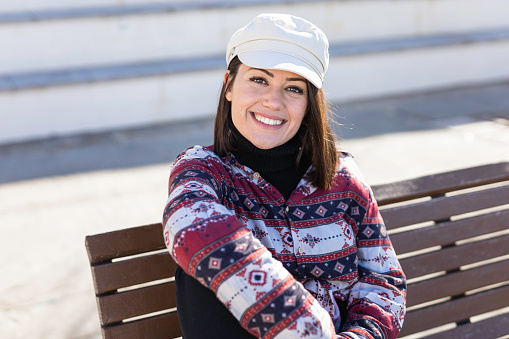 Young and beautiful woman is happy and laughing. She is sitting on a park bench.