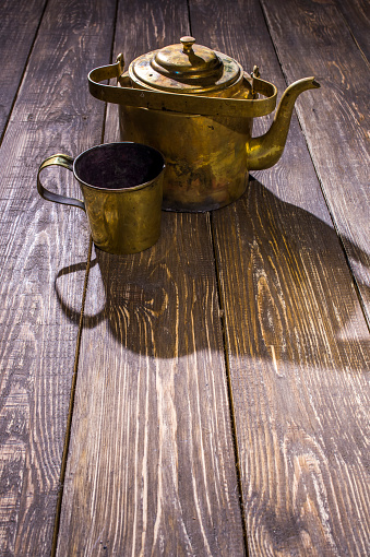brass kettle with a bronze bowl on wooden table