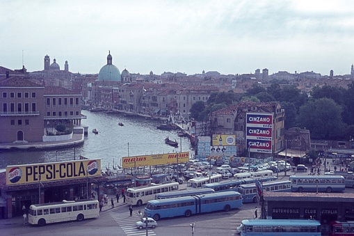 Piazzale Roma, Venice, Veneto, Italy, 1963. The bus station at Piazzale Roma in Venice. Furthermore: tourists, locals, buses, buildings, advertising and a waterway (canal).