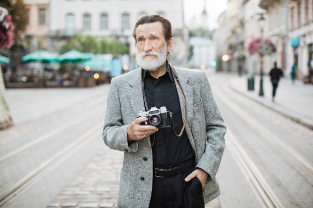 istock Senior man holding old photo camera while standing outdoors 1310485302