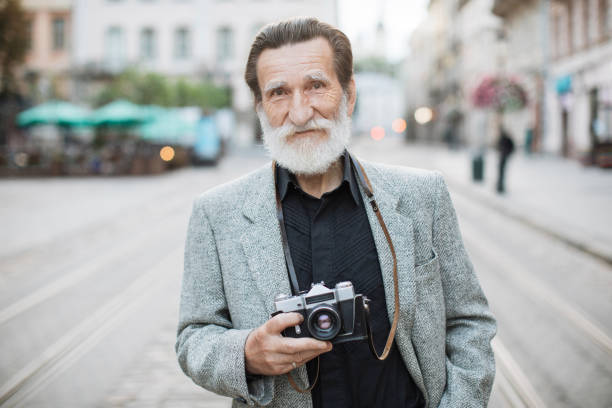istock Senior man holding old photo camera while standing outdoors 1310485310