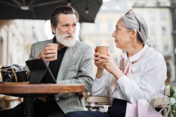 istock Aged couple relaxing on cafe terrace with coffee and tablet 1310486460