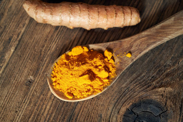 istock Turmeric powder on a wooden spoon and fresh turmeric root 1310487939