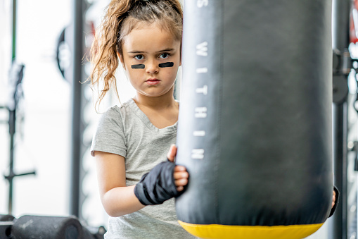 7 year old girl taking boxing lessons in a training facility as a form of exercise and self defence.