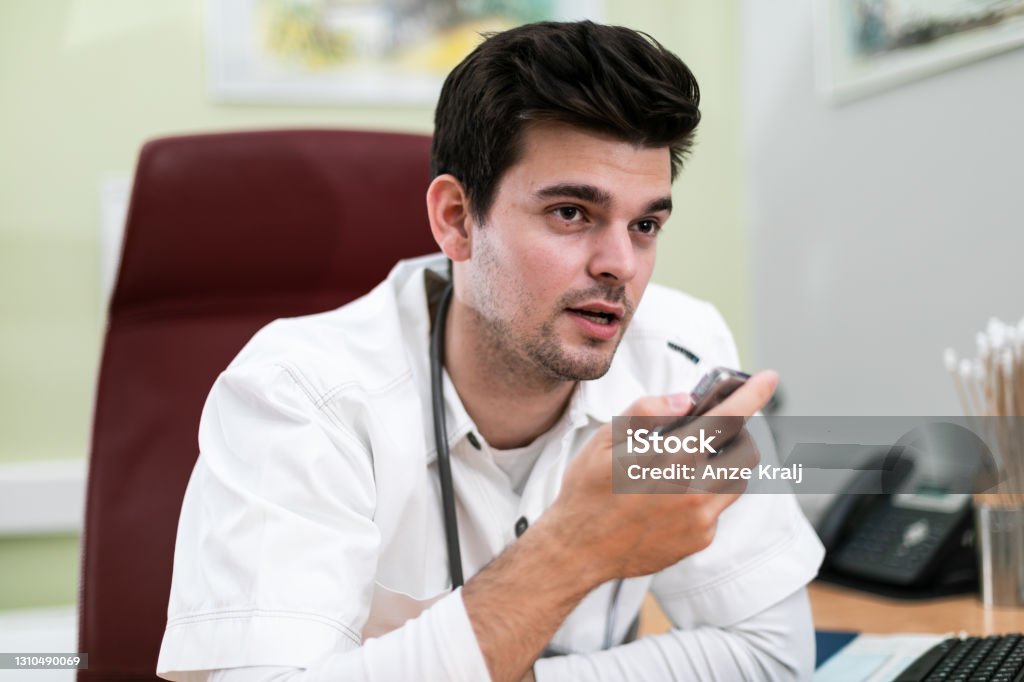 Young doctor talking into Dictaphone  - type recorder Young doctor talking into Dictaphone - type recorder Dictaphone Stock Photo