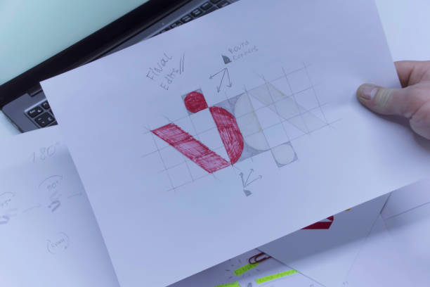 istock Creative workplace of a Graphic Designer. A man in the office is developing a logo on the table against the background of printed sketches and a laptop. 1310490205