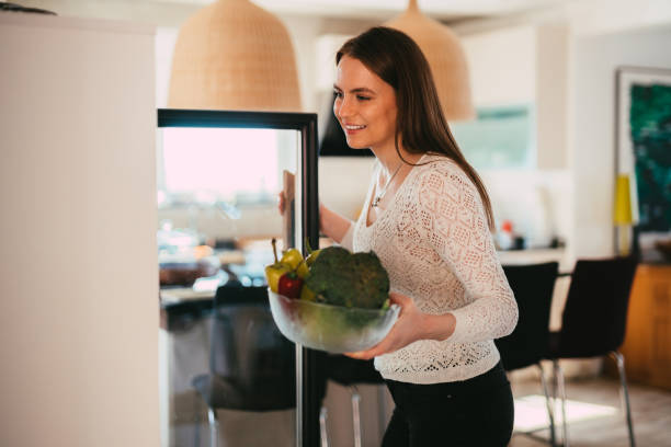 istock Young woman taking out vegetables from a refrigerator 1310490998