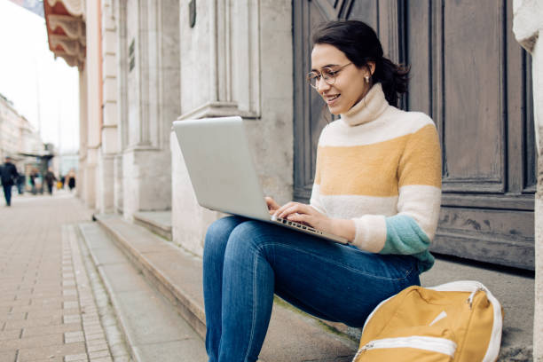 istock Beautiful student sitting in front of her university and studying online 1310493393