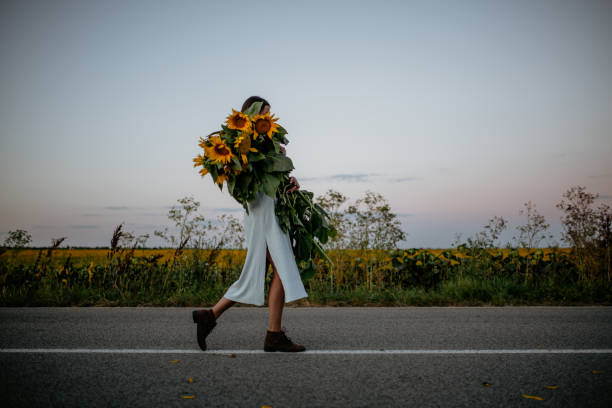 Happy child with bouquet of beautiful sunflowers in summer sunflower field on sunset. Mother day concept