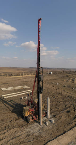 Excavation at a construction site, diesel pile driving machine with rumble and smoke drives piles deep into the ground to ensure the strength of the foundation of the future structure