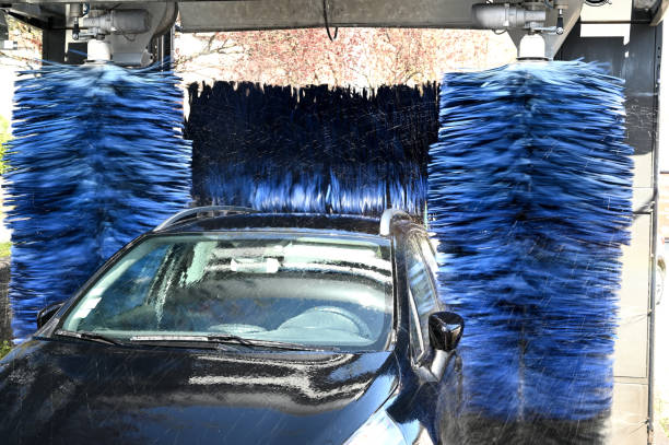 schwarzes auto wird an einer automatischen autowaschanlage gewaschen - autowaschanlage stock-fotos und bilder