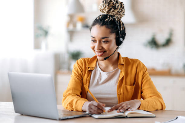 istock Concentrated confident friendly african american girl in headset, call center operator, manager, agent of support service, conducts online consultation, video briefing, taking notes, smiling friendly 1310501865