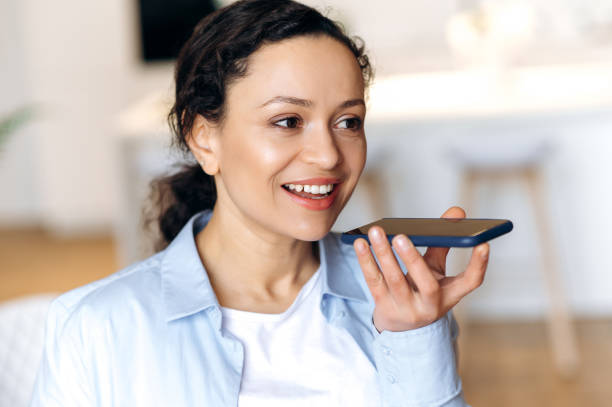 istock Attractive successful mixed race brunette attractive woman, using smartphone, talking to friends or colleagues on speakerphone or recording audio message, looking away, smiling friendly 1310502620