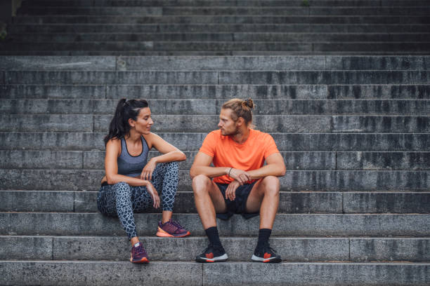 istock Happy Couple Talking while Sitting on the Stairs after a Workout 1310506244