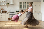 Happy grandmother have fun dancing with little granddaughter