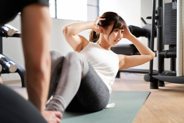 Asian women doing sit-ups under the guidance of a personal trainer Asian women doing sit-ups under the guidance of a personal trainer sit ups stock pictures, royalty-free photos & images