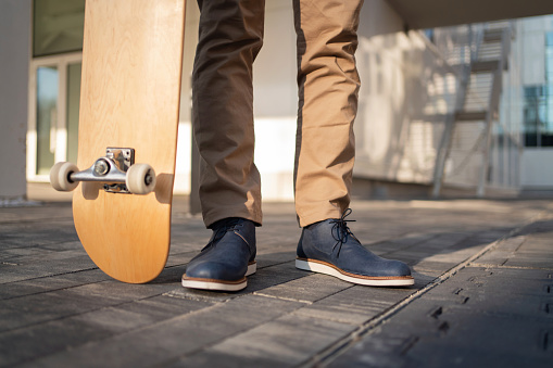 Close-up of an unrecognizable man standing with his skateboard.