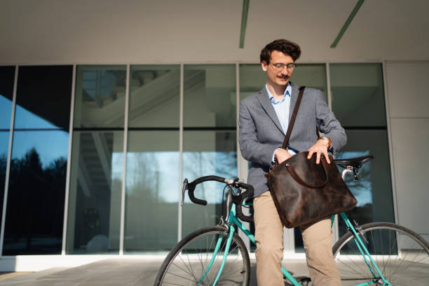istock Young businessman searching his bag while leaning on a bicycle 1310516203