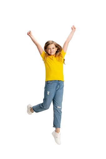 Happy kid, girl isolated on white studio background. Looks happy, cheerful. Copyspace for ad. Childhood, education, emotions, business, facial expression concept. Jumping high, running celebrating