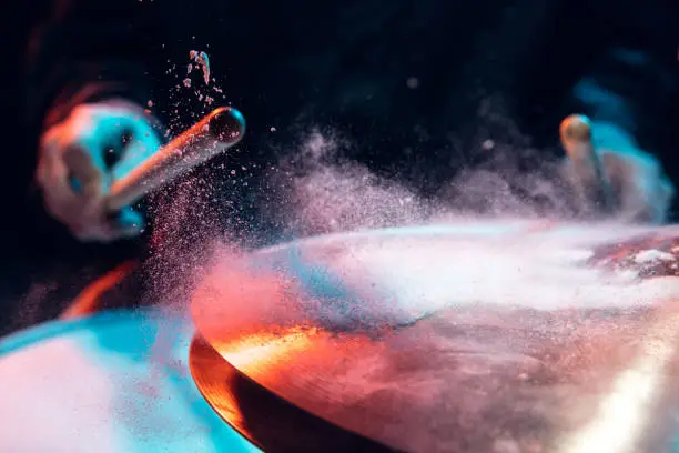 Motion. Drummer's rehearsing on drums before rock concert. Man recording music on drumset in studio. Neon light, trendy fluid colors. Concept of music, hobby, entertainment, fun. Close up, flying powder