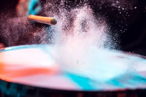 Motion. Drummer's rehearsing on drums before rock concert. Man recording music on drumset in studio. Neon light, trendy fluid colors. Concept of music, hobby, entertainment, fun. Close up, flying powder