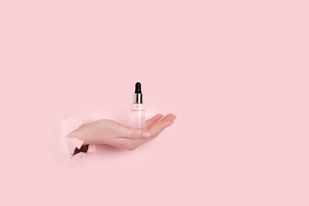 istock Female hand holding hyaluronic bottle from torn paper 1310520782