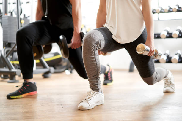 Asian couple doing dumbbell front lunge Asian couple doing dumbbell front lunge strength training stock pictures, royalty-free photos & images