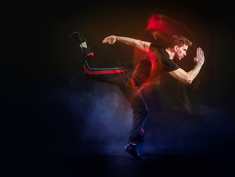 Latin athlete running on black background with light effects