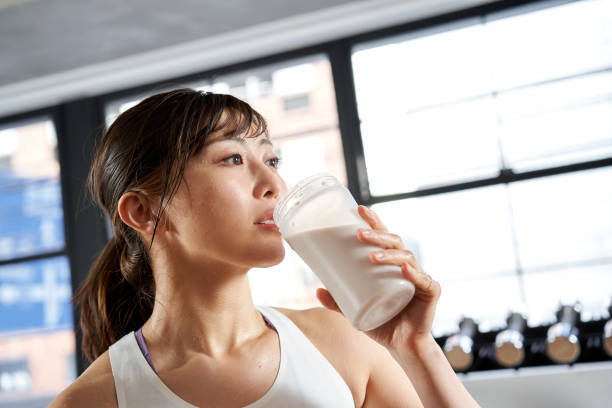 donne asiatiche che bevono proteine dopo l'allenamento - bevanda proteica foto e immagini stock