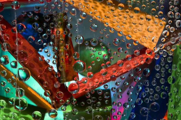 istock Translucent drops of water fall down against the turquoise-malachite background with multicolored geometric figures. 1310537174