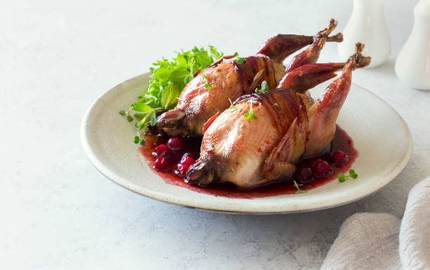 Oven baked quails served with berry sauce on stone plate close up stock photo