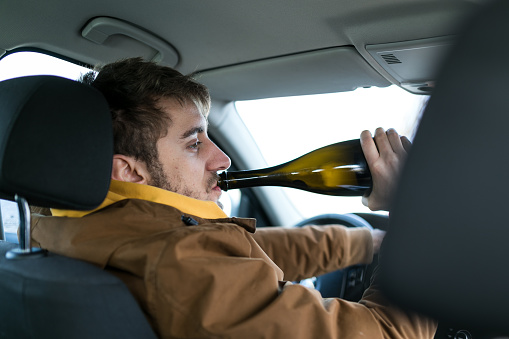 Man drinking alcohol while driving car ,concept drive safely.