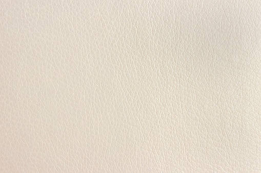 The surface of artificial beige leather used for furniture upholstery. Uniform light texture.