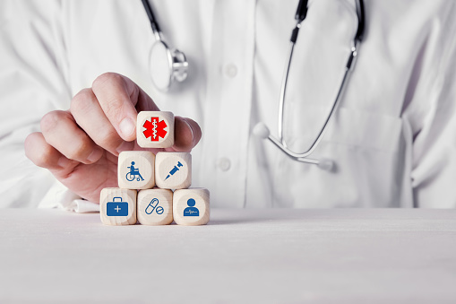 Hand of a doctor placing wooden cubes with medical health icons. Health care and medicine concept.