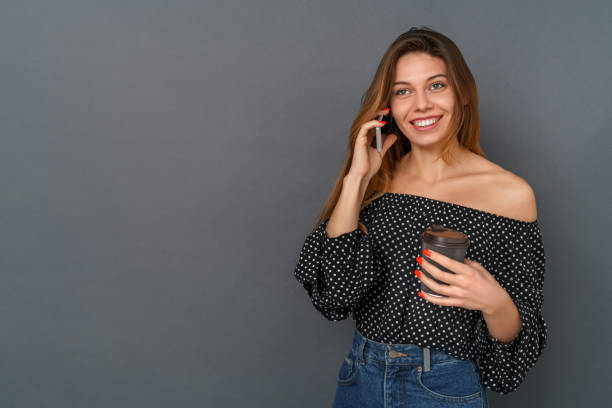 istock Young woman casual studio isolated on gray talking on phone drinking coffee 1310554773