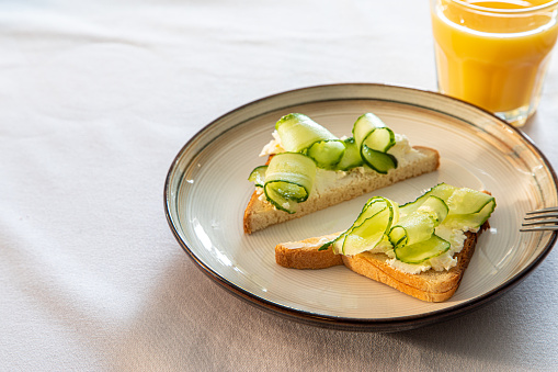 Cucumber and cream cheese toast on a plate. Healthy vegetarian diet concept.