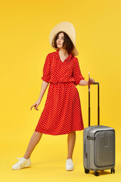 istock woman with suitcase going traveling on yellow background. 1310559478