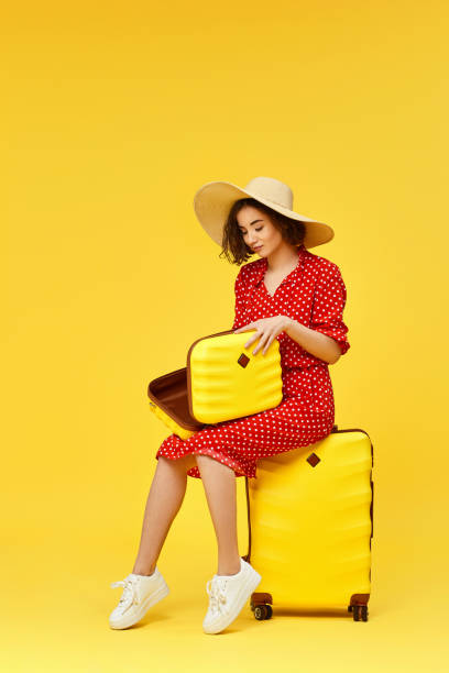 istock woman with suitcase going traveling on yellow background. 1310559543