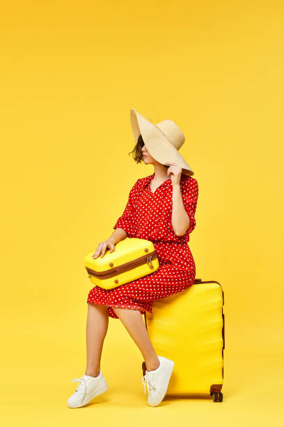 istock woman with suitcase going traveling on yellow background. 1310559562