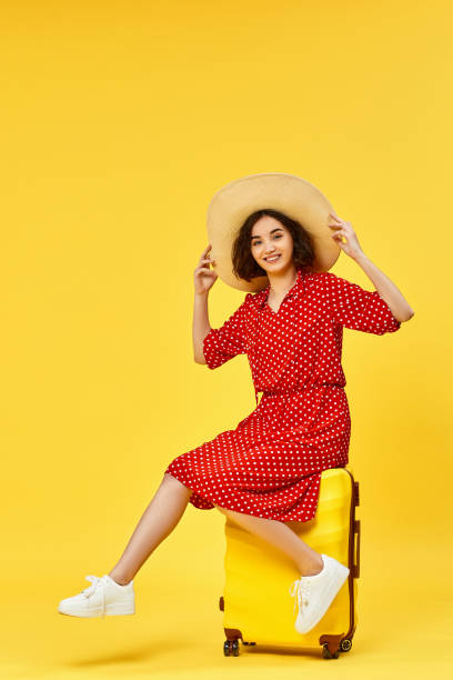 istock woman with suitcase going traveling on yellow background. 1310559567