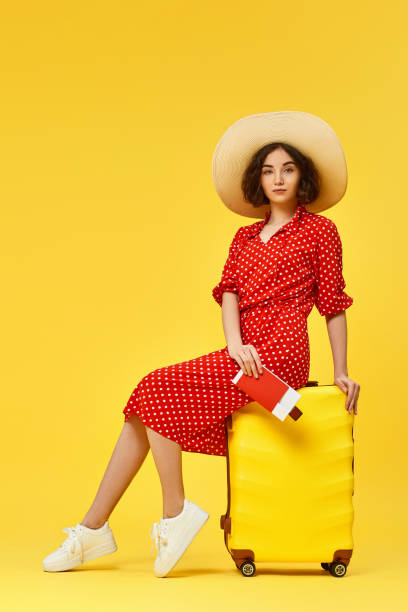 istock woman with suitcase going traveling on yellow background. 1310559572