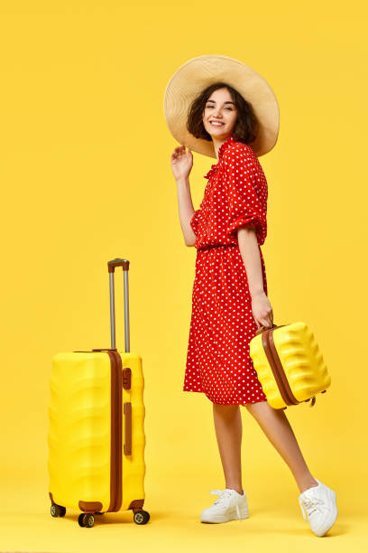 istock woman with suitcase going traveling on yellow background. 1310559581