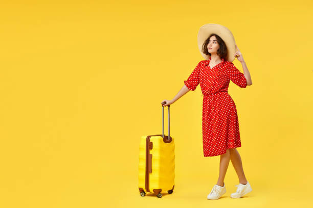 istock woman with suitcase going traveling on yellow background. 1310559589