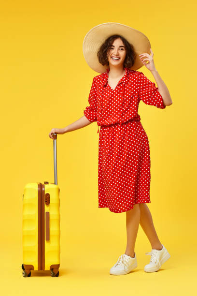 istock woman with suitcase going traveling on yellow background. 1310559594
