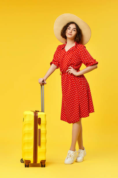 istock woman with suitcase going traveling on yellow background. 1310559600